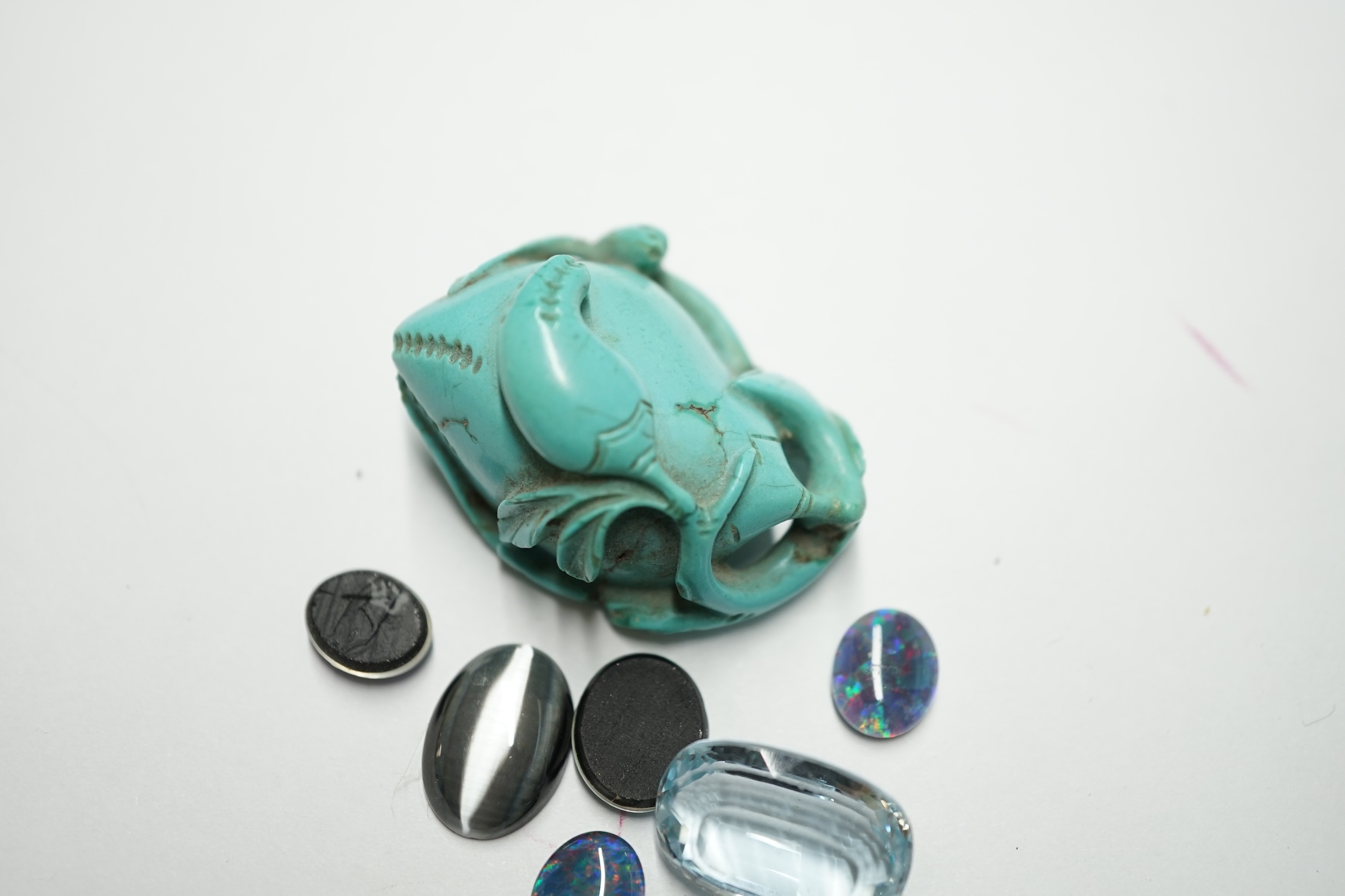 A turquoise carving and a small group of unmounted stones including opal doublets and chatoyant and a blue topaz. Condition - fair